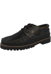 Zapato náutico de cuero negro con puntera redondeada, suela de goma con relieve y costuras en contraste. Presenta tres ojales y un emblema de la marca en el lateral.