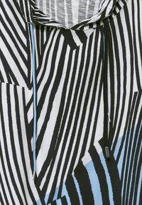 Tissu à rayures noires et blanches avec des accents bleus, comportant une capuche et des cordons de serrage. La texture semble lisse avec un motif géométrique audacieux.