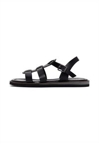 Black leather sandal featuring multiple vertical and horizontal straps, a buckle closure, flat sole, and a smooth textured finish.