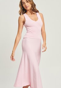 Vestito pink senza maniche con corsetto aderente e fondo midi svasato, realizzato in tessuto morbido con una leggera texture. Design a V.