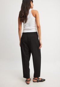 Makuva mblack yakareba-soro ane relaxed fit, akasanganiswa nezvimwe zvine texture yakatsetseka, mapoketi maviri kumashure, uye zipper-fly yekuvhara. Yakasanganiswa ne tank top chena.