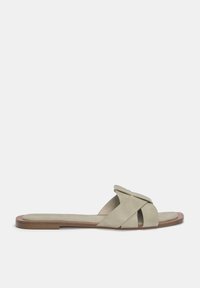 Texturerad ljusgrön sandal med korsade remmar, platt sula och en minimalistisk design. Dämpad fotbädd och öppen tå för komfort.