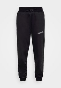Zwarte katoenen sweatpants met een trekkoord in de taille, elastische boorden en een witte "CALVIN KLEIN" logo op de linker dij. Voorzien van een gladde textuur.