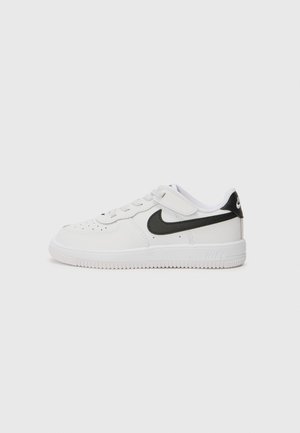 Fehér bőr sportcipő fekete részletekkel, kerek orral, perforált felsőrésszel, lapos fűzőkkel és texturált gumitalppal, oldalán a Nike logóval.