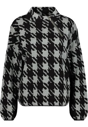 Schwarz-grauer Pullover mit Hahnentrittmuster, hohem Kragen und diagonalem Reißverschlussdetail an der linken Schulter.