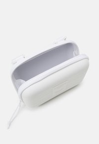 White hard-shell case with textured surface, zip closure, and a grey fabric interior. Features a logo plate on the front.