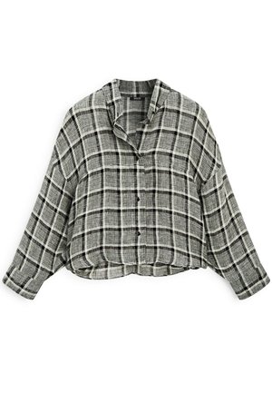 Korte button-up shirt in zwart-wit geruite patroon. Ruime snit, lange mouwen en een kraag. Gemaakt van zachte stof met een textuurafwerking.