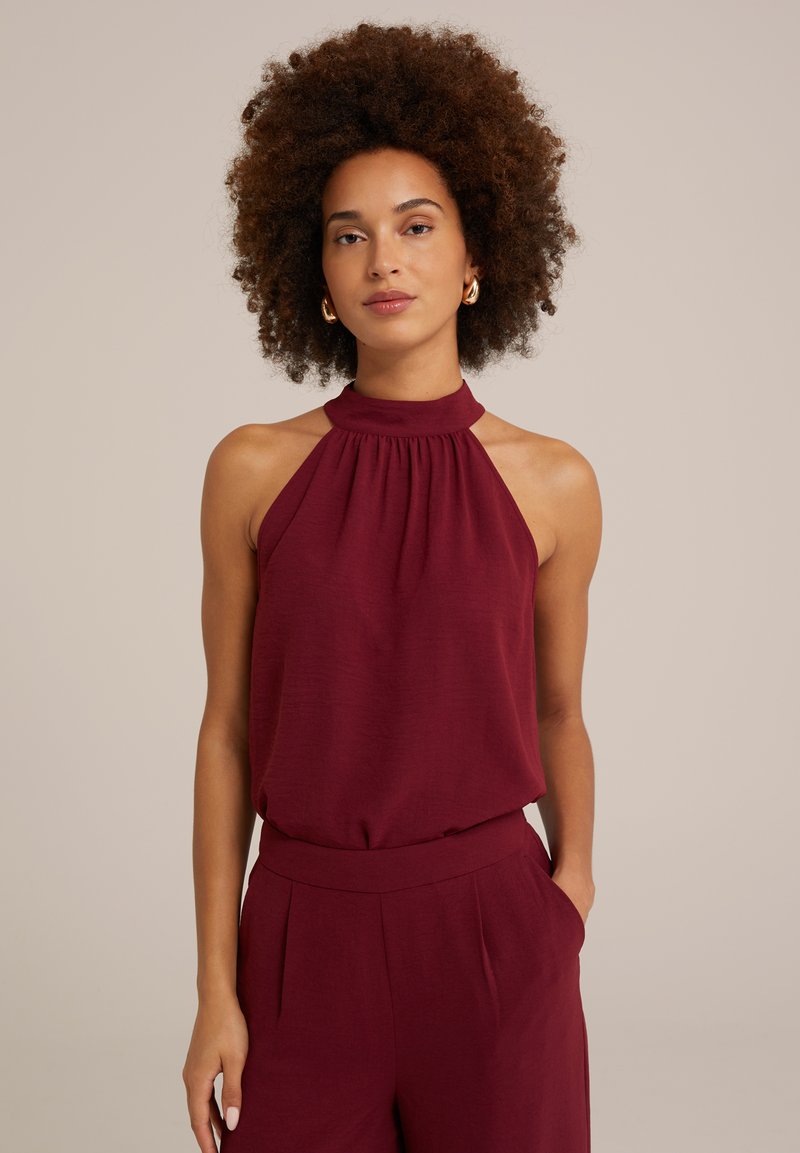 Burgundijas halter top, kas izgatavots no mīksta auduma, ar savilkta kakla izgriezumu un atklātiem pleciem. Savienots ar atbilstošām augstvērtīgām biksēm.