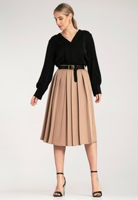 Czarna, długosleeve bluzka z dekoltem w kształcie litery V; beżowa, plisowana spódnica midi; czarny pasek z okrągłą klamrą; czarne, sandałki na obcasie.