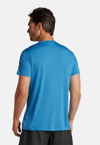 Blå atletisk t-shirt med korte ærmer, tekstureret stof, rund halsudskæring og løs pasform, parret med mørke shorts.