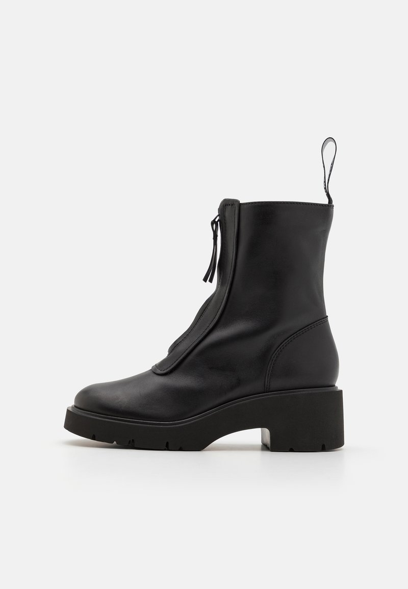 Black leather ankle boot with a zip closure, chunky platform sole, and a smooth texture. Features a pull tab at the back for easy wear.