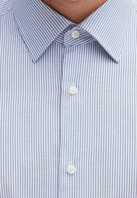Pánská košile s vertikálními modrými a bílými pruhy, límcem na knoflíky a bílými knoflíky na předním pruhu. Bavlněný materiál.
