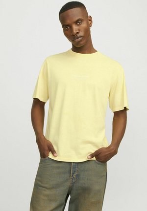 Svijetložuti pamučni T-shirt s okruglim izrezom i kratkim rukavima, na kojem se nalazi mali bijeli otisnuti logo "Originals Studio" na prsima.