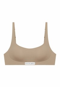 Soutien-gorge beige en tissu lisse, avec un décolleté en forme de bateau, de larges bretelles, et une étiquette rectangulaire portant l'inscription "GOD SAVE QUEENS" à l'avant.