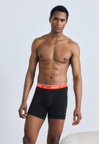 Fekete pamut boxeralsó piros Nike derékpánttal, testhez simuló kialakítású és sima textúrájú. Bal lábszáron kis Nike logóval.