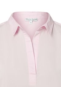 Camicia rosa chiaro con colletto, con un'apertura parziale sulla patta frontale e un'etichetta "Marie Lund Copenhagen" visibile all'interno del colletto.