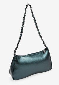 Bolso de mano metálico en color azul verde con forma curvada, cierre de cremallera y una correa de cadena hecha de eslabones negros interconectados. Textura suave con un acabado brillante.