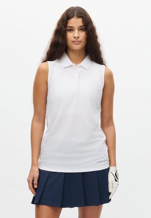 Hvid ærmeløs polo med krave og fem knapper, lavet af glat stof. Sammen med en marineblå plissee nederdel. Hvid handske på venstre hånd.