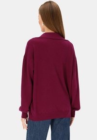 Bordowy sweter dziany z kołnierzykiem, szerokimi rękawami i prążkowanym dołem; miękka faktura i luźny krój idealny do noszenia na warstwach.