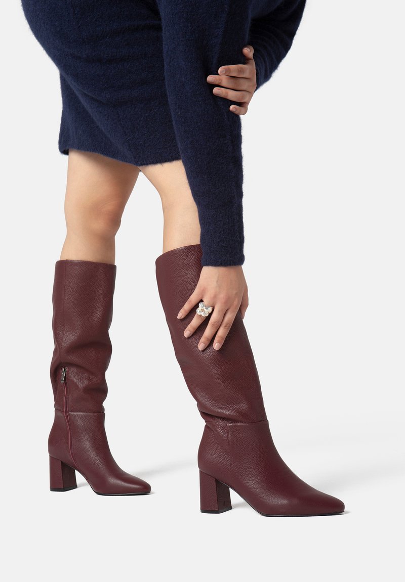 Stivali in pelle bordeaux al ginocchio con tacco a blocco e chiusura con zip, caratterizzati da una superficie liscia e una punta appuntita.