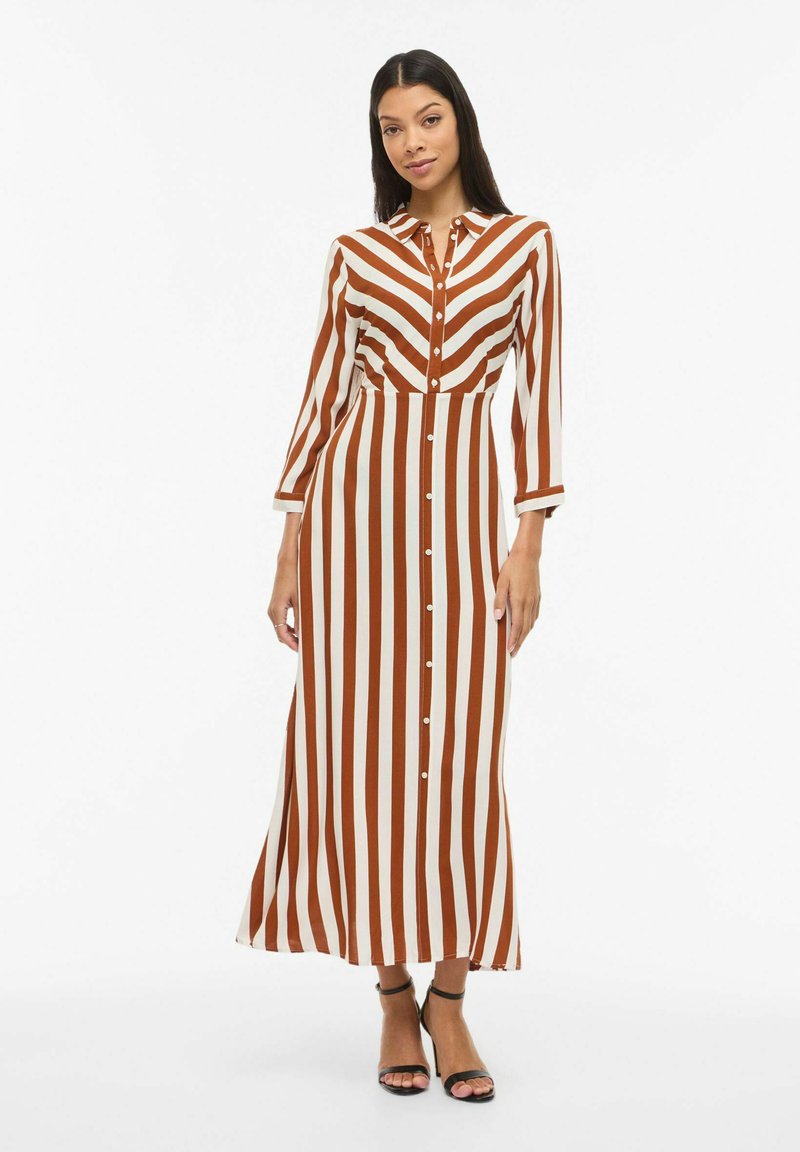 Robe longue à rayures de couleur marron et crème, avec fermeture à boutons et col. Manches longues aux poignets retroussés, fabriquée en tissu lisse.