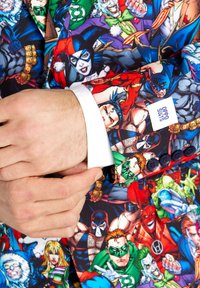 Colorful comic-themed suit jacket featuring various superheroes and villains, made from smooth fabric, with a white shirt cuff visible at the wrist.