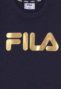 Felpa blu navy con un grande logo "FILA" in oro metallizzato. Presenta una scollatura a coste e una texture del tessuto morbida, adatta per bambini di 5-6 anni.