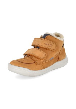 Bruine leren kinderschoen met witte zool, twee klittenbandsluitingen en een zachte fleece voering zichtbaar bij de enkelopening.