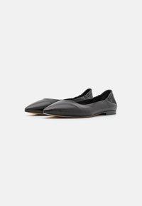 Bailarinas de cuero negro con un diseño de punta afilada, textura suave y un estilo minimalista. Cuentan con un tacón bajo para mayor comodidad.