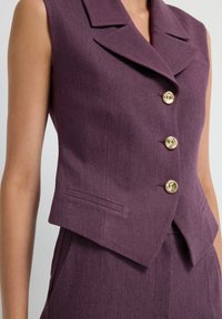 Violet sleeveless blazer with a tailored fit, sharp lapels, four metallic gold buttons, and a pocket detail on the left side.