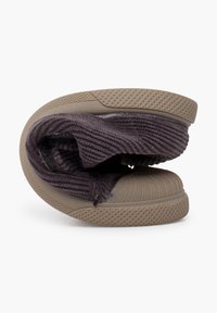 Brown slip-on shoe featuring a rubber sole with a ridged toe and interior ribbed fabric, displayed in a folded position.