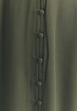 Khaki zelená látka s hladkou texturou, s centrální linií pěti knoflíků potažených látkou a jemnými šicími detaily.