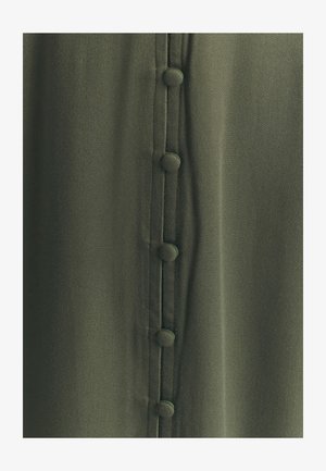 Tkanina w kolorze khaki o gładkiej fakturze, z centralną linią z pięciu guzików pokrytych tkaniną oraz subtelnymi detalami szwów.