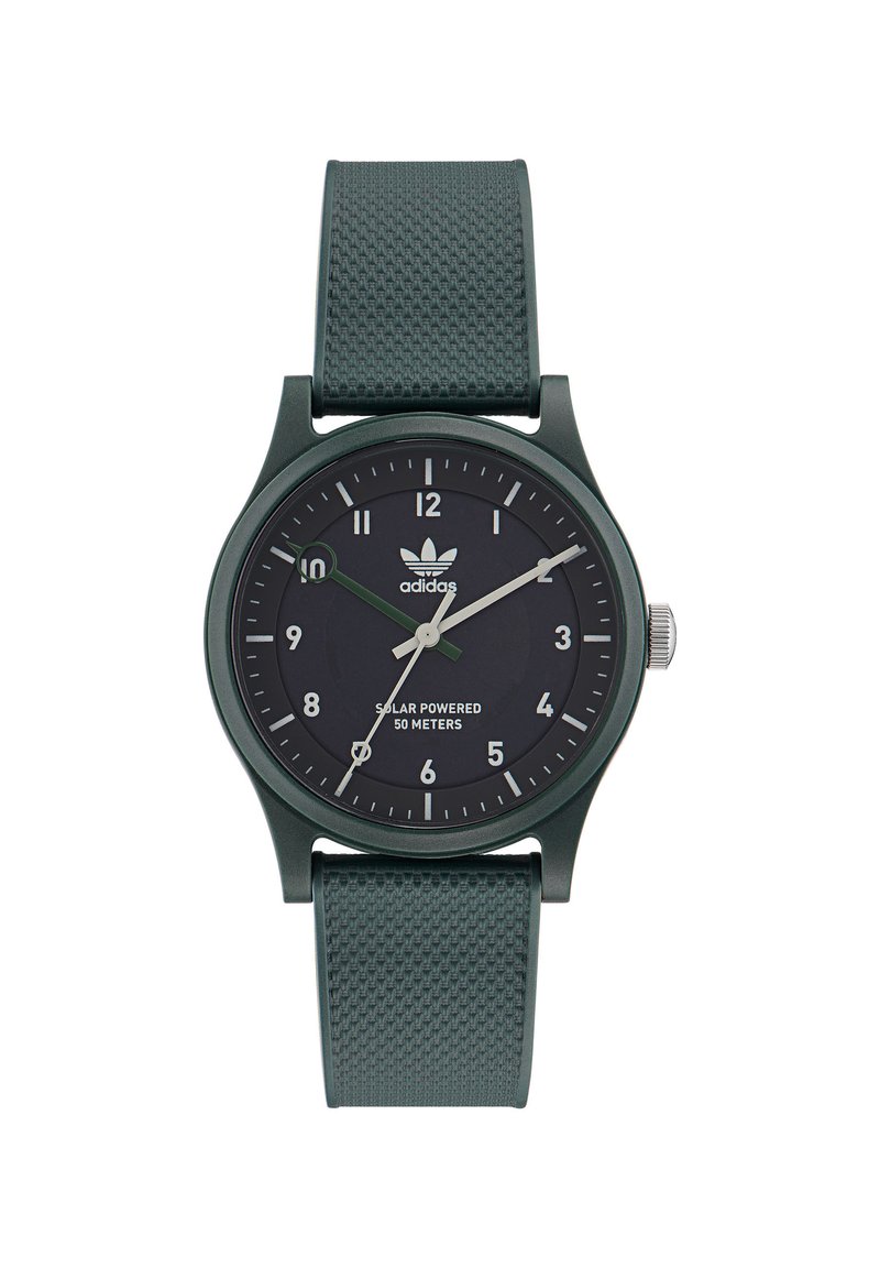 Montre solaire verte avec un bracelet texturé, un cadran noir, des index horaires blancs et verts, et un accent en acier inoxydable sur la couronne.