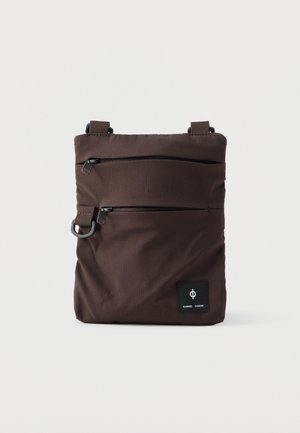 Smeđi platneni crossbody ranac s dva zatvorena džepa, podesivim trakama i logom na prednjoj strani. Glatka tekstura, pravokutni oblik.