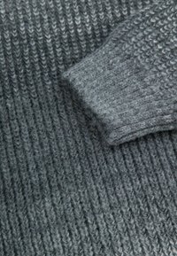 Szary dziany sweter o ribbowanej fakturze, z złożonym mankietem w odcieniu nieco jaśniejszego szarości. Miękki i ciepły.