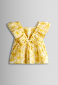 Rochiță de bebeluș galbenă și albă, cu mâneci mari volanate și imprimeu cu flori de margarete pe un material ușor.