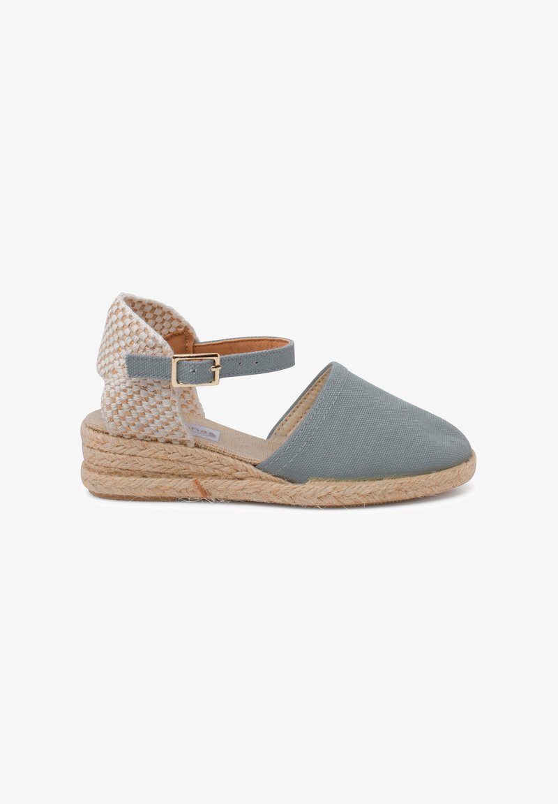 Espadrille en toile grise avec un dos tissé, une bride à la cheville et une semelle intermédiaire en jute. Présente une pointe ronde et un dessus en tissu texturé.