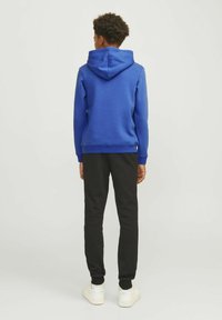 Blaues Kapuzensweatshirt aus weichem Stoff, kombiniert mit schwarzen Sweatpants. Verfügt über eine Kängurutasche und gerippte Bündchen. Schlichtes Design.