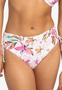 Bas de bikini avec une base blanche présentant un motif floral dans les tons rose, orange et vert. Les liens sur les côtés et les détails de fronces améliorent l'ajustement.