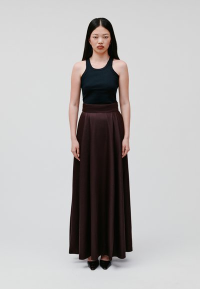 Black ribbed tank top paired with a high-waisted, flowing burgundy skirt, creating a smooth silhouette. Model wearing pointed black heels.