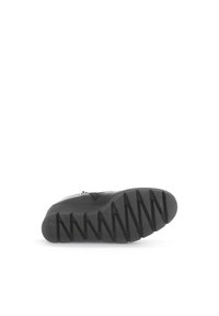 Chaussure en cuir noir avec une semelle en caoutchouc texturé présentant des motifs de semelle en zigzag. Détail de fermeture éclair sur le côté ajoutant fonctionnalité au design.