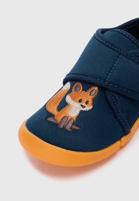Navy blue fabric shoe with orange rubber sole featuring an embroidered fox design. Velcro strap for easy adjustment.