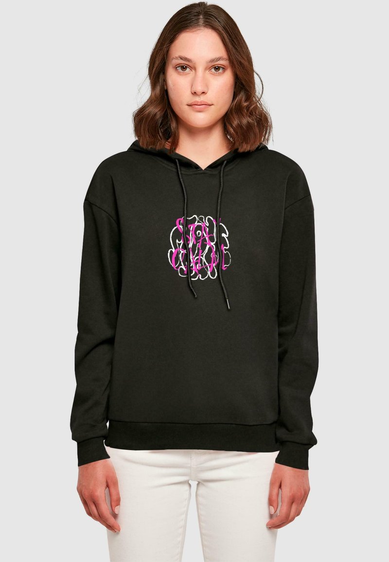 Hoodie noir avec un graphisme en rose et blanc sur le devant. Fabriqué en matériau doux, il est doté d'une capuche avec cordon de serrage et de poignets côtelés. Un jean blanc est porté.