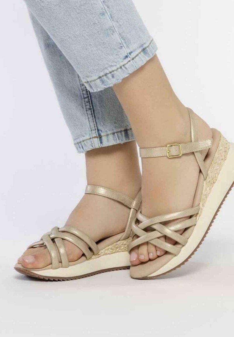 Sandalias de cuña beige con diseño de tiras cruzadas, textura metálica y una suela intermedia de estilo espadrille tejida, con suela de goma.