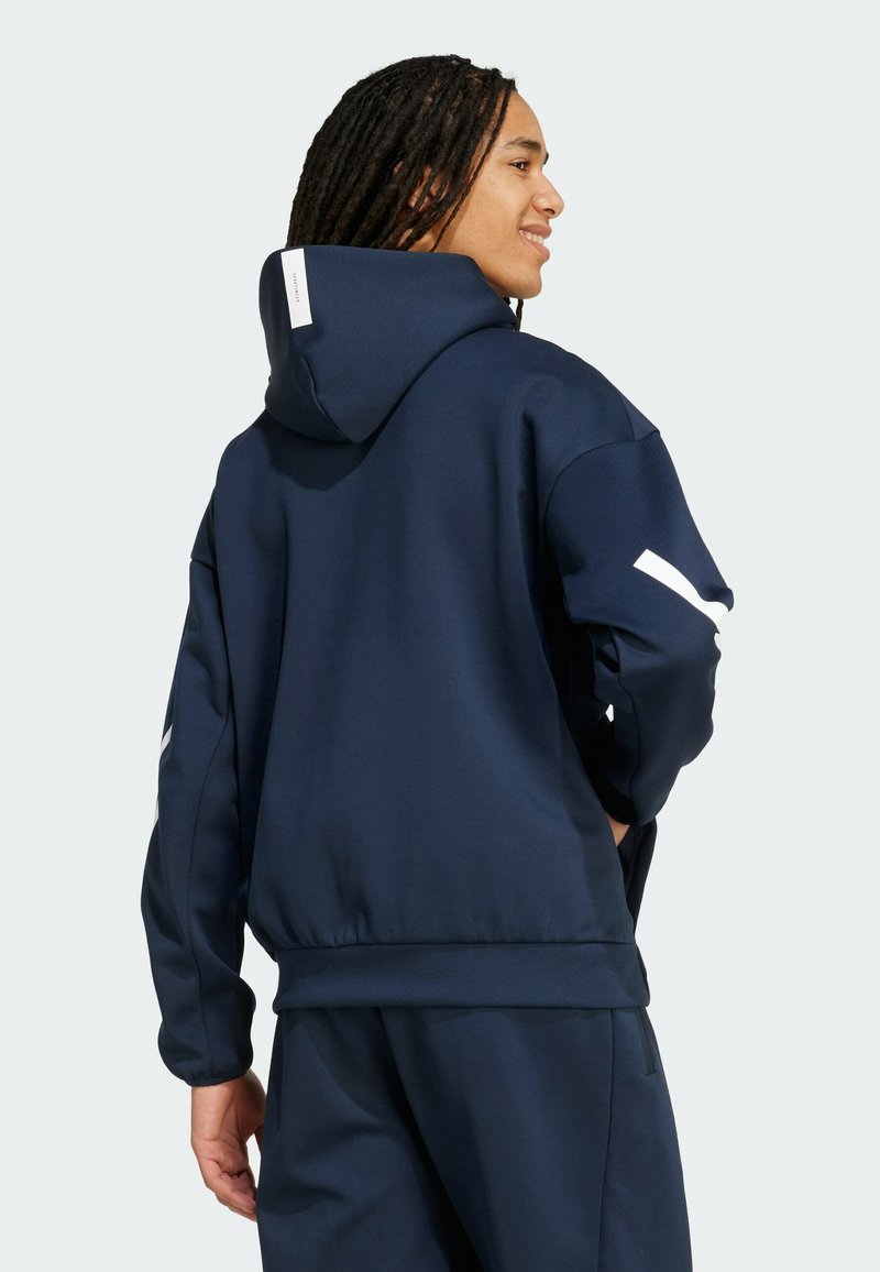 Donkerblauwe hoodie gemaakt van textuurstof, met een grote capuchon, ribgebreide manchetten en een witte accentstreep op de mouw.