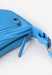 Blaues Lederhandtasche mit dreieckiger Form, einem reißverschlussfach und einem Metallsnapdetail. Glatte Textur und verstellbarer Schulterriemen inklusive.