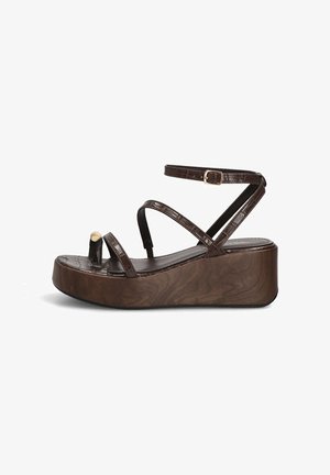 Sandalia de plataforma marrón con tres tiras finas, hebilla en el tobillo y una suela de cuña elevada con un sutil patrón de vetas de madera.