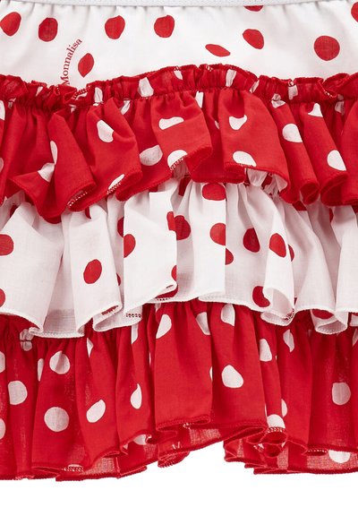 Gonna arruffata a pois rossi e bianchi realizzata in tessuto leggero, con più strati e dettagli arricciati in vita.