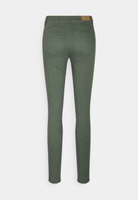 Vaqueros skinny de color verde oscuro con una textura suave, que presentan un diseño clásico de cinco bolsillos y una pequeña etiqueta en la cintura trasera.